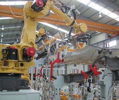 A robot arm constructs an object in a factory.