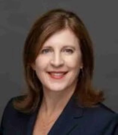 A headshot of a brunette woman in a navy blazer.